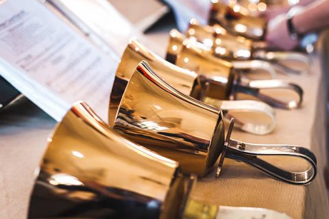 Golden handbells on table with sheet of notes